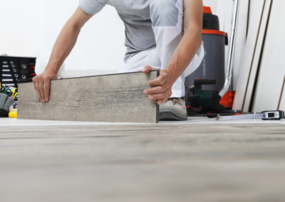 Arbeiterhände beim Verlegen von Holzlaminat-Vinylboden. Holzböden Haus Renovierung.